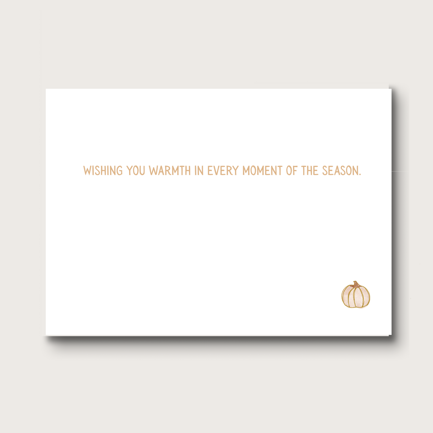 White card with text that reads 'WISHING YOU WARMTH IN EVERY MOMENT OF THE SEASON.' and a small pumpkin illustration in the bottom right corner.