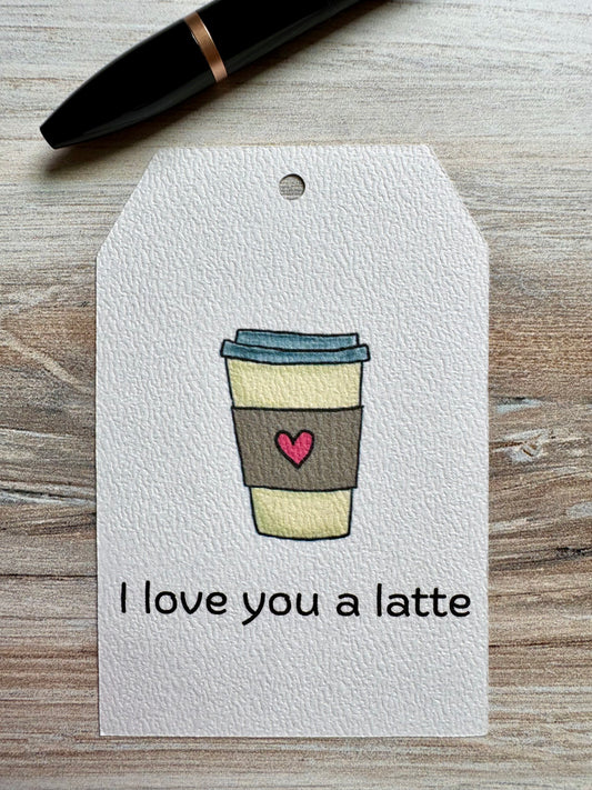 Gift Tag with a coffee cup illustration and 'I love you a latte' text placed on a wooden surface.