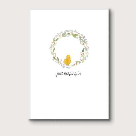 Greeting card with a watercolor chick  and floral wreath on a white background with the words "just peeping in" 
